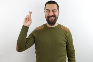 Bearded man wearing casual clothes and glasses gesturing finger crossed smiling with hope and eyes closed. luck and superstitious concept.