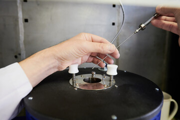 a drop of gasoline on the tip of the syringe needle before placing it, like a sample, in a test chamber to check the quality, chemical composition, performance in a special laboratory