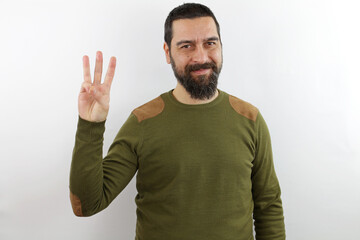 Bearded man wearing casual clothes showing and pointing up with fingers number three while smiling confident and happy.