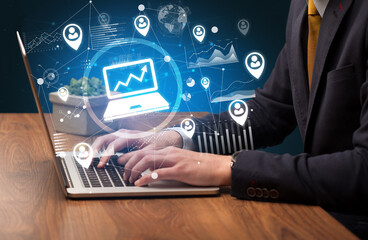 Business hand working on laptop with laptop icons coming out from the screen, successful business concept