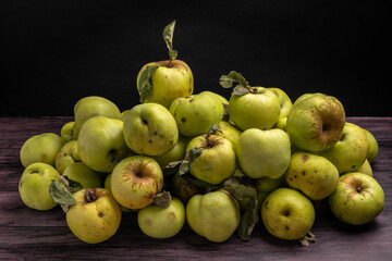 a pile of apples on a dark wooden table