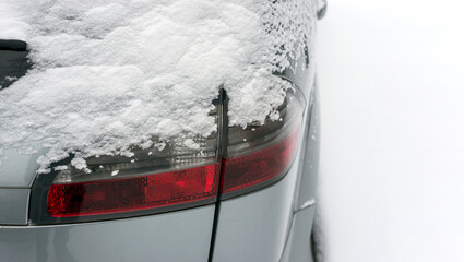 Closeup of rear light of car parked in the street covered by the snow