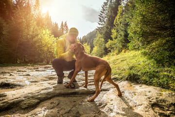 Traveler Man trekker with him dog walk around mountains in sunny day. Backpacker walking in Outdoors. Health care, authenticity, sense of balance and calmness.