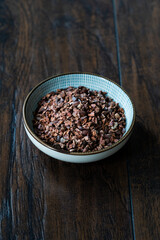 Chocolate Cacao Nibs or Cocoa Nibs in Bowl Ready to Use on Dark Wooden Surface.