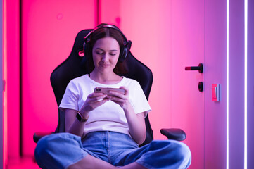 Young female teenage cyber sport gamer play mobile game by smartphone on eSport tournament - obrazy, fototapety, plakaty