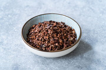 Chocolate Cacao Nibs or Cocoa Nibs in Bowl Ready to Use on Dark Wooden Surface.