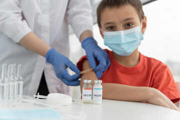 Fototapeta premium happy boy in medical mask after vaccination from covid. Doctor's hands glue plaster on injection site. Vaccination concept