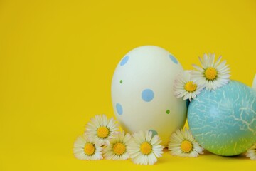 Easter holiday. Easter white speckled and blue eggs and chamomile flowers on a bright yellow background.Spring festive easter background in pastel colors	.Easter light festive background