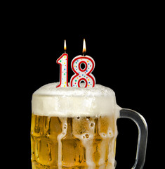 number 18 candle in beer mug for birthday celebration isolated on black 