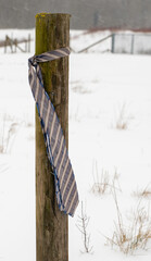 A tie hangs on a wooden fence in a snowing cold day concept unemployment.