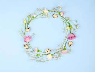 Easter composition. Easter eggs, flowers, paper blank on pastel blue background. Flat lay, top view, copy space, mock up.