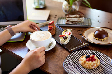 coffee in women's hands, sweet desserts on a wooden table