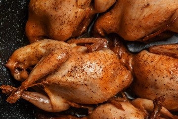 Delicious fried quail carcasses in a frying pan, close. Top view, flat lying. the concept of dietary nutrition.