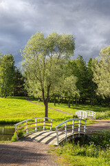 cozy park landscape with two white wooden bridges, paths and a stormy sky