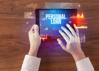 Close-up of hands holding tablet with PERSONAL LOAN inscription, modern business concept