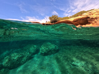 Underwater split photo from rocky sea cave formation in calm sea beach of Avlaki, Porto Rafti, Mesogeia, Attica, Greece