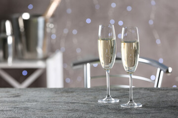 Glasses of champagne on grey table. Space for text