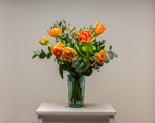 A bouquet of peach and orange colored roses on a small table.