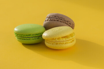 French cookies lie on a trendy yellow background. Yellow, green, brown. Macaroon. The concept is a French traditional pastry. Horizontal photo.