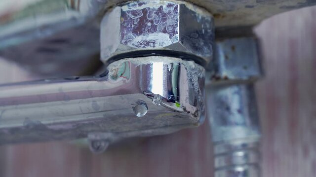 the old, rusty faucet in the bathroom is dripping. water drips from the tap, on the connection close-up. The mixer is old and needs to be replaced. reckless use of resources