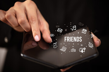 Businessman holding a foldable smartphone with FRIENDS inscription, social media concept