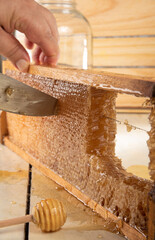 Honeycomb, cutting honeycombs from the medeira with a knife. Wooden background, selective focus.