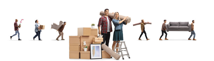Smiling man and woman with a pile of boxes carrying a carpet and other people moving household items