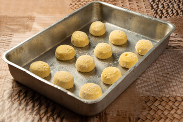 Cheese bread from Brazil, frozen cheese bread being placed in the baking pan, selective focus.