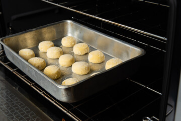Cheese bread from Brazil, frozen cheese bread being placed in the oven for baking, selective focus.
