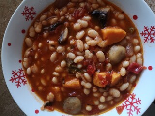 Cooked beans on the pot in tomato sauce with mushrooms carrot sweet potato and red onion 