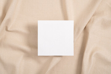 White square invitation card mockup on beige textile background
