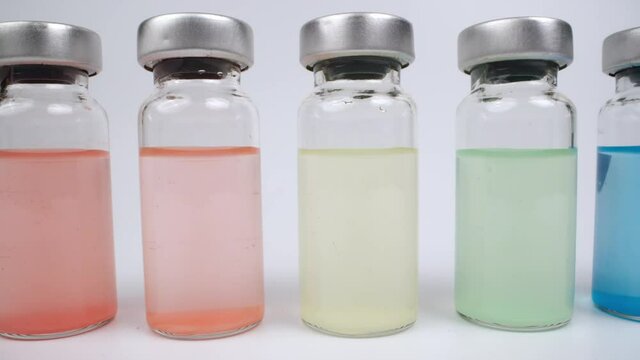 Glass vials of with different coloured liquids against white background