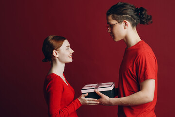 Valentine Day Gift. Happy Young Couple with Valentine's Day Present isolated on red background.
