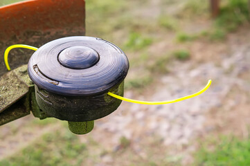 Close-up of the trimmer. Nylon yellow grass trimmer string and head. The coil of a manual lawn...