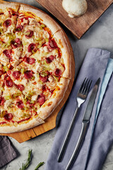 pizza with sausages with cutlery on gray background top view