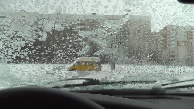 Car windshield brushes slide on frozen snow and ice. Condensate. Poor visibility of the road. Frost on the car window. Weather. Winter blizzard. view from the inside.