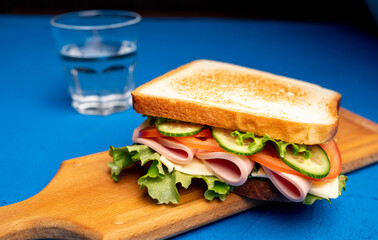 Sandwich with bacon and vegetables on a dark background. Macro