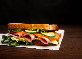 Sandwich with bacon and vegetables on a dark background. Macro