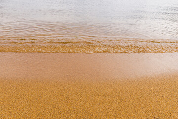 Close-up of a water edge and yellow sand summer beach background with copy space.