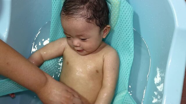Happy and adorable baby boy playing water during taking a bath