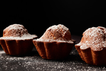 cupcakes sprinkled with powdered sugar on a black background
