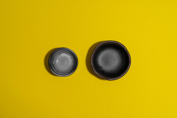 two empty dark plates on yellow background