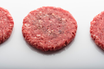 Closeup shot of fresh raw burger patties on a white surface