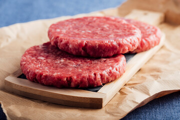 Closeup shot of fresh raw burger patties on a wooden board