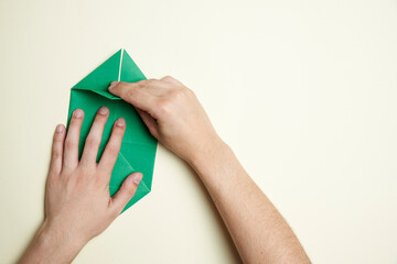Creation process of an origami shamrock: young hands folding a piece of paper