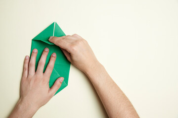 Creation process of an origami shamrock: young hands folding a piece of paper - Powered by Adobe