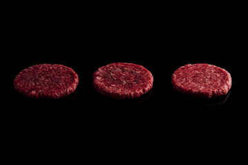 Closeup shot of fresh raw burger patties on a black surface