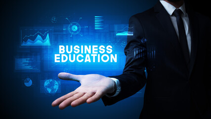 Hand of Businessman holding BUSINESS EDUCATION inscription, business success concept