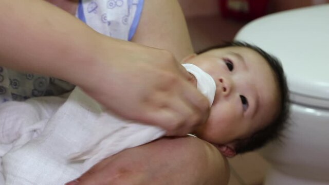 A Chinese Asian mother wipe face of adorable baby using clean handkerchief