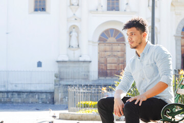 Portrait of hispanic young man sitting in front of the San Jose cathedral in Antigua Guatemala -...